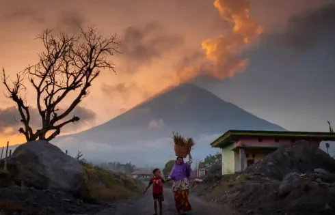 Seorang ibu dan anak berjalan bersama dengan latar gunung, menggambarkan kasih sayang dan ketangguhan keluarga. (fotografer: Sunaryo | Lokasi: Pronojiwo, Lumajang)