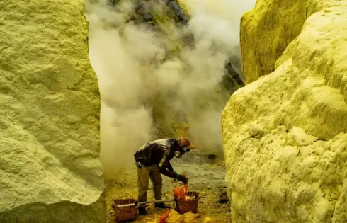 Penambang belerang bekerja di tengah kepulan asap dan dinding kawah, menunjukkan keberanian menghadapi kerasnya alam. (fotografer: Rismiyanto | Lokasi: Kawah Ijen, Banyuwangi)